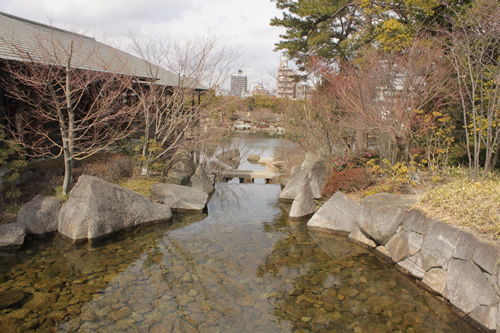 滝の上流から遠くにビルが見えます